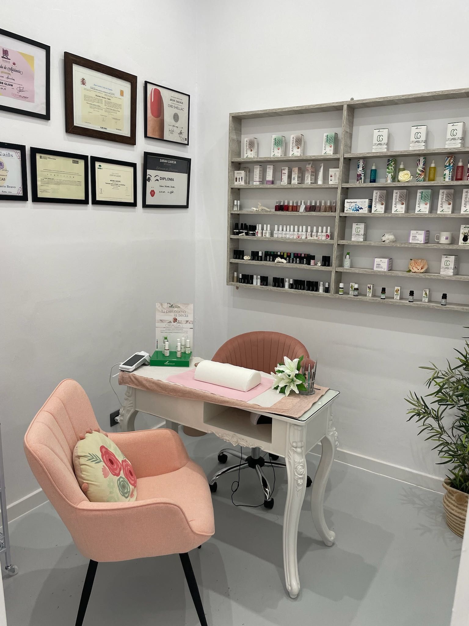 Cabina de manicura con la silla rosa y el tocador blanco.